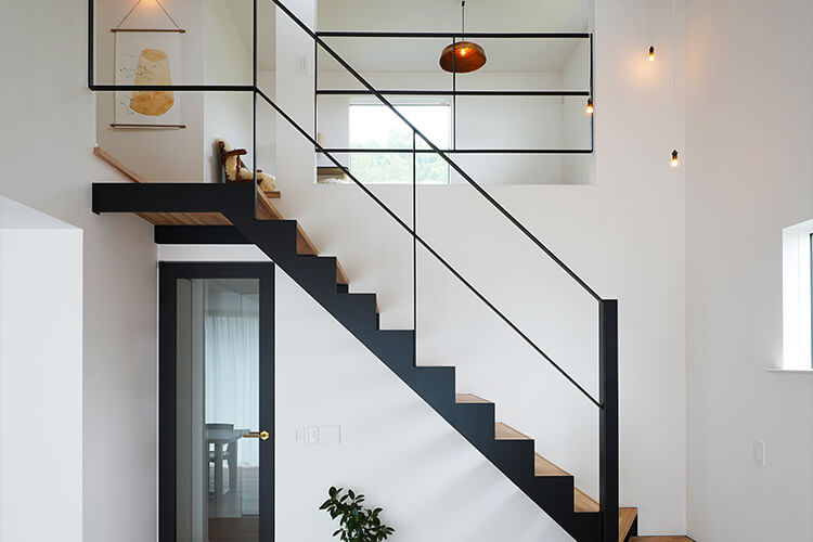 軽やかな造作の吹抜け階段は家の印象を決めます。階段下のガラスドアも黒い枠で印象を統一し心地の良い吹抜け空間が完成